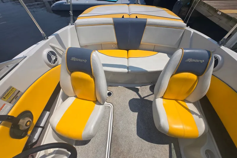 Slide: The Image of 2007 Sea Ray 185 Sport boat interior with yellow and gray seating, docked by water. - 1