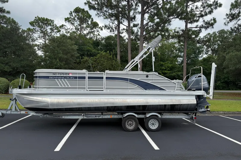 The Image of 2022 Bennington LX 22 Swingback pontoon boat on trailer, parked in a lot. - 1