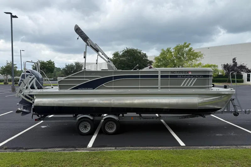 Slide: The Image of 2022 Bennington LX 22 Swingback pontoon boat on trailer in parking lot. - 9