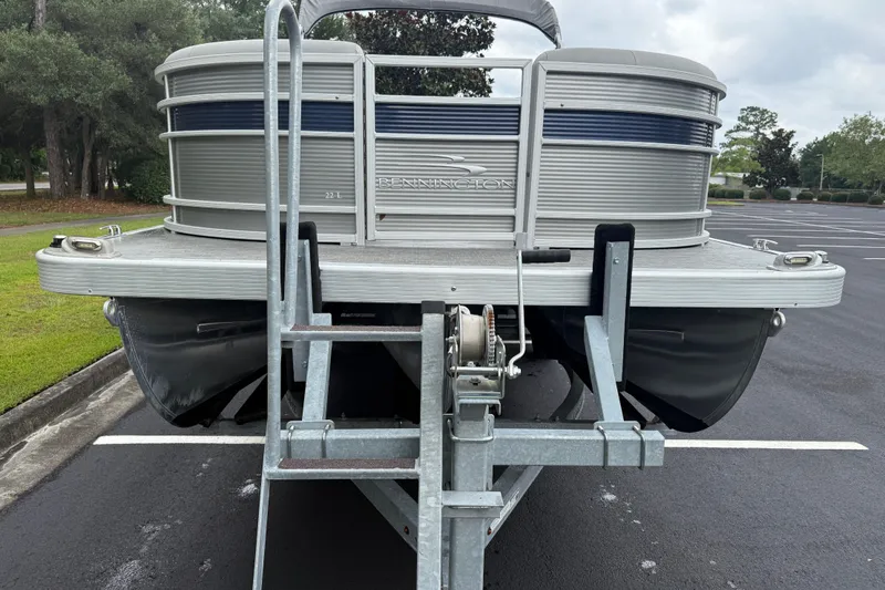Slide: The Image of 2022 Bennington LX 22 Swingback pontoon boat on trailer in parking lot. - 12