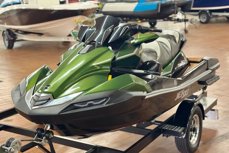 Slide: The Image of 2025 Kawasaki JET SKI ULTRA 160 LX in showroom, featuring sleek green design on trailer. - 0