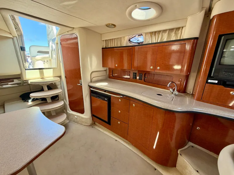 Slide: The Image of The interior of a 2003 Sea Ray Sundancer 320 features a well-equipped galley with wooden cabinets. - 11