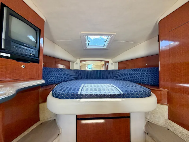 Slide: The Image of The cabin of a 2003 Sea Ray Sundancer 320 with a bed and a small TV. - 12