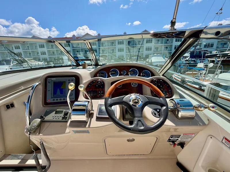 Slide: The Image of The cockpit of a 2003 Sea Ray Sundancer 320 with a wood steering wheel and modern instruments. - 4