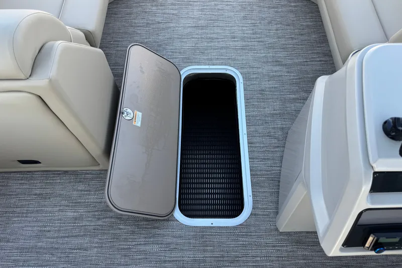 Slide: The Image of Open storage compartment on 2027 Godfrey EX 2286 SBX boat, featuring beige seating and gray flooring. - 12