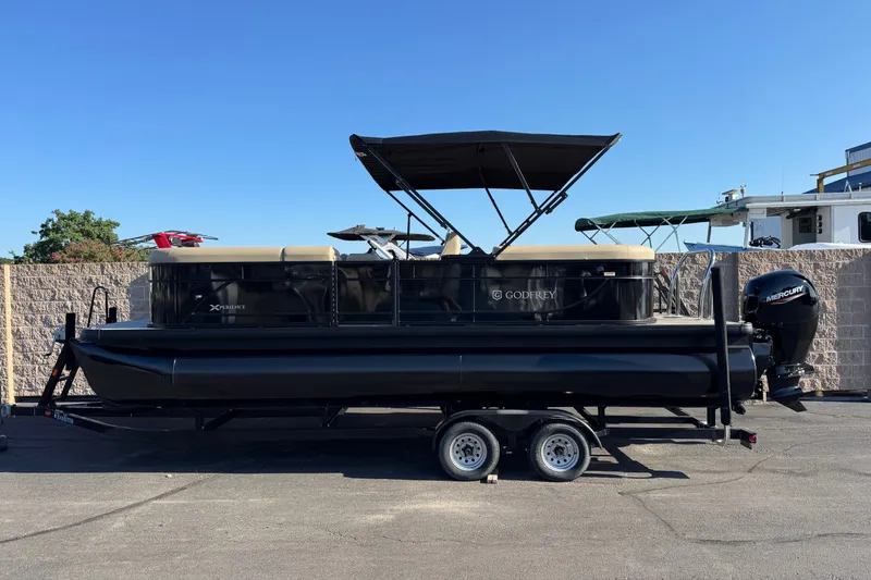 The Image of 2027 Godfrey EX 2286 SBX pontoon boat on trailer, parked outdoors. - 0