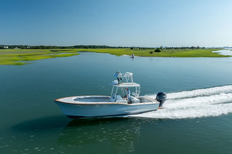 Slide: The Image of 2023 Harrison Boatworks 28 cruising on a serene waterway under a clear blue sky. - 32