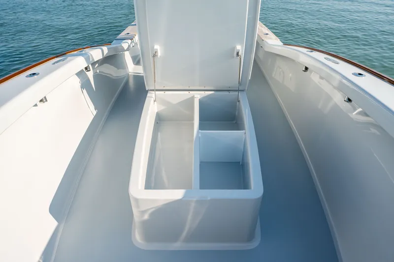 Slide: The Image of 2023 Harrison Boatworks 28 with open storage compartment on deck, docked on calm water. - 48