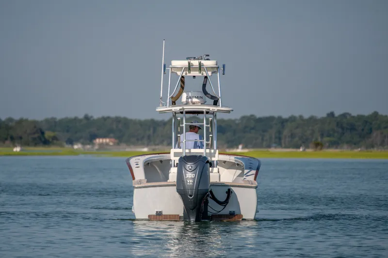 Slide: The Image of 2023 Harrison Boatworks 28 cruising on calm water, rear view with outboard motor. - 41