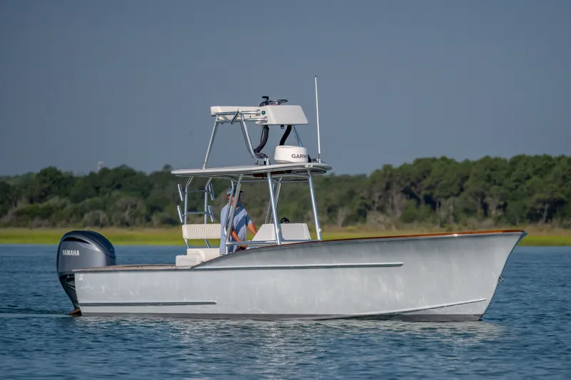 Slide: The Image of 2023 Harrison Boatworks 28 on water, featuring Yamaha engine, with lush green shoreline in background. - 16