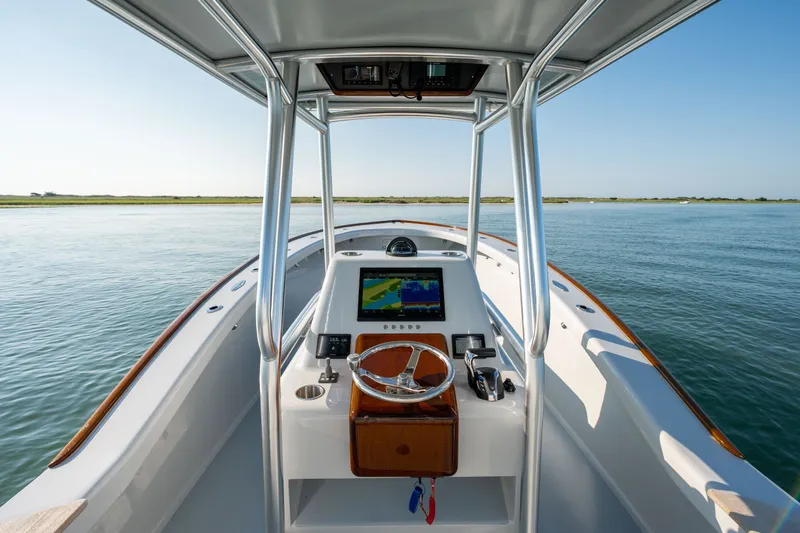 Slide: The Image of Harrison Boatworks 28, 2023 model, featuring a sleek helm and navigation system on calm waters. - 8