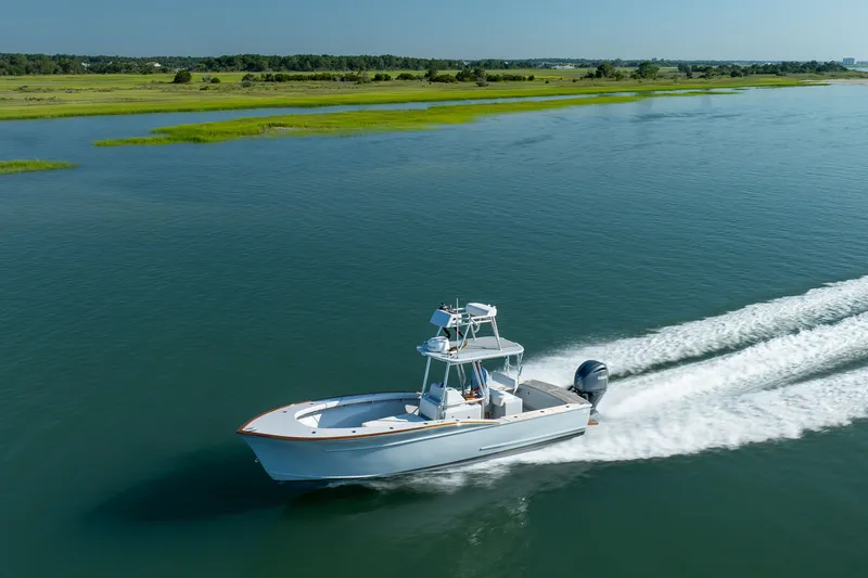 Slide: The Image of 2023 Harrison Boatworks 28 cruising on a serene waterway with lush green shoreline. - 31