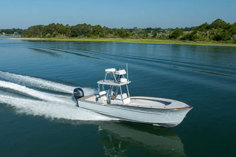 Slide: The Image of 2023 Harrison Boatworks 28 cruising on calm water near a lush shoreline. - 18