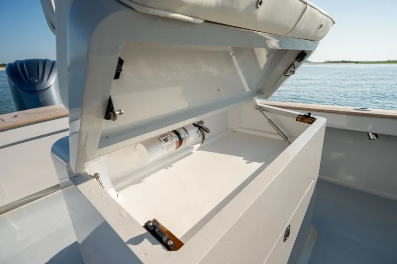 Slide: The Image of Open storage compartment on 2023 Harrison Boatworks 28, featuring a fire extinguisher inside. - 49
