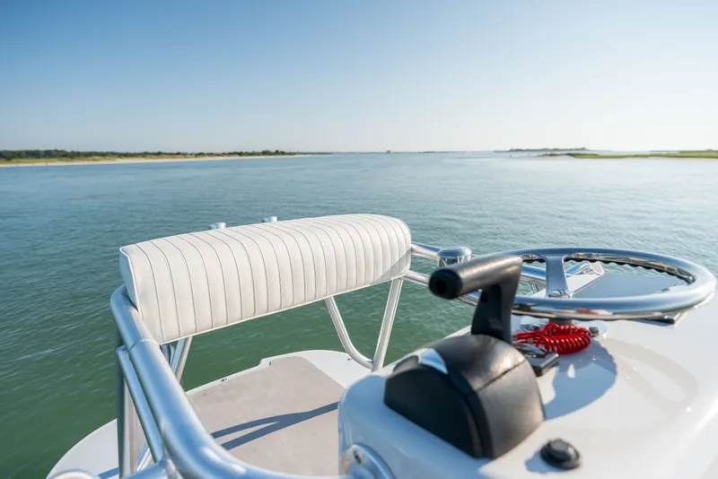 Slide: The Image of 2023 Harrison Boatworks 28 helm view, showcasing steering wheel and throttle on calm waters. - 28