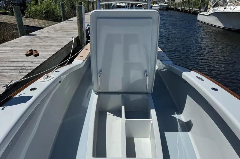 Slide: The Image of 2023 Harrison Boatworks 28 with open storage compartment, docked by a wooden pier. - 7