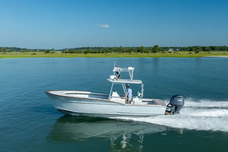 Slide: The Image of 2023 Harrison Boatworks 28 cruising on a serene lake under a clear blue sky. - 12