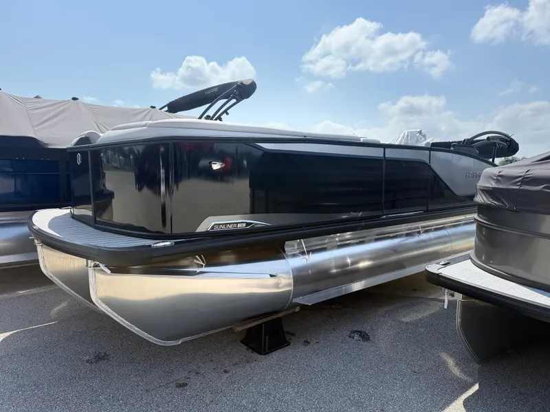 Slide: The Image of A sleek pontoon boat with a black hull and silver pontoons, parked under a blue sky. - 3