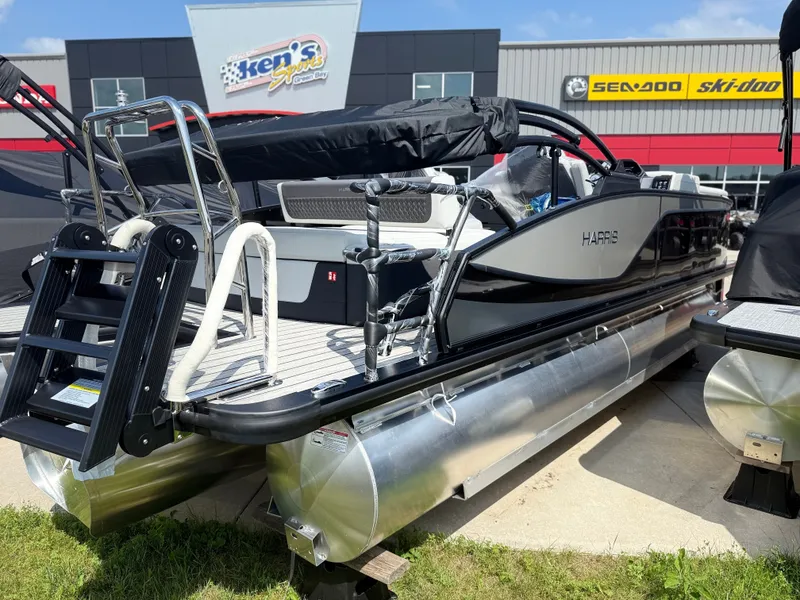 Slide: The Image of A 2027 Harris FloteBote SUNLINER 230 TRI-TOON SLDH is displayed outdoors. It features sleek black accents and a sturdy pontoon hull. - 5