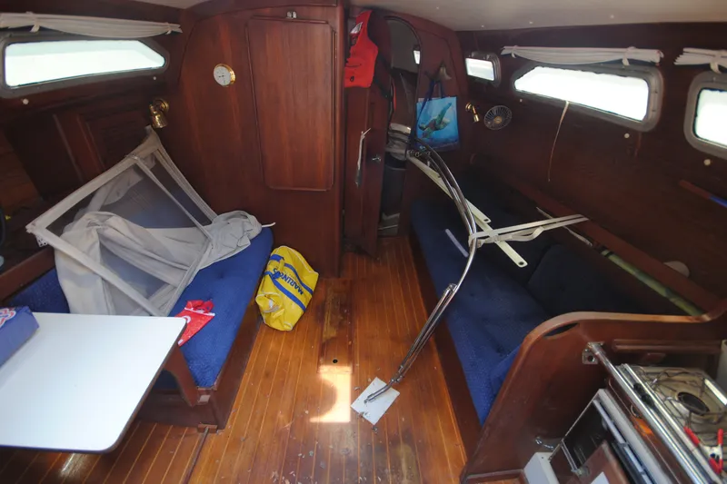 Slide: The Image of Interior of a 1987 Tillotson-Pearson 28 sailboat with wooden paneling and blue seating. - 11
