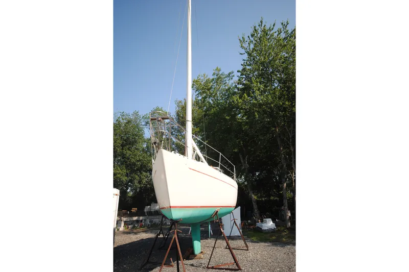 Slide: The Image of 1987 Tillotson-Pearson 28 sailboat on stands, surrounded by trees and clear sky. - 4