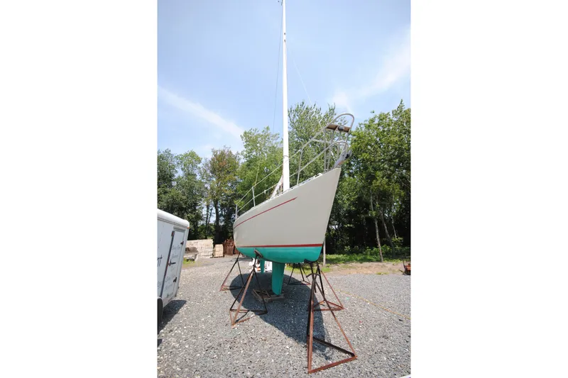 Slide: The Image of 1987 Tillotson-Pearson 28 sailboat on stands, surrounded by trees and gravel. - 3