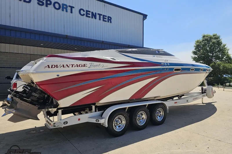 Slide: The Image of 2001 Advantage 34 Offshore boat on trailer, vibrant red and blue design, parked outside sports center. - 11