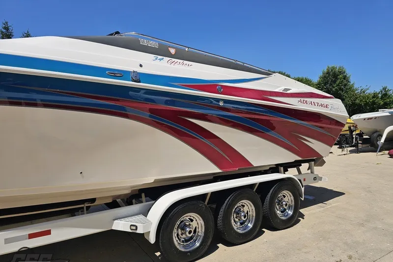 Slide: The Image of 2001 Advantage 34 Offshore boat with vibrant red and blue graphics on a trailer. - 18