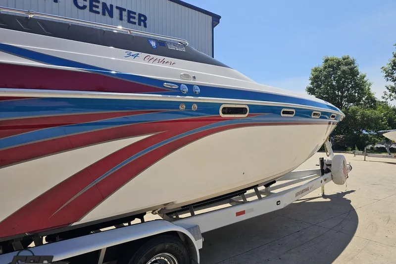 Slide: The Image of 2001 Advantage 34 Offshore boat with vibrant red and blue design on trailer. - 9