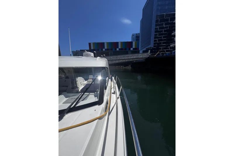 Slide: The Image of 2021 Beneteau Antares 8 docked near modern buildings under a clear blue sky. - 30