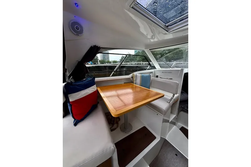 Slide: The Image of Interior of 2021 Beneteau Antares 8 boat with wooden table and cushioned seating. - 2