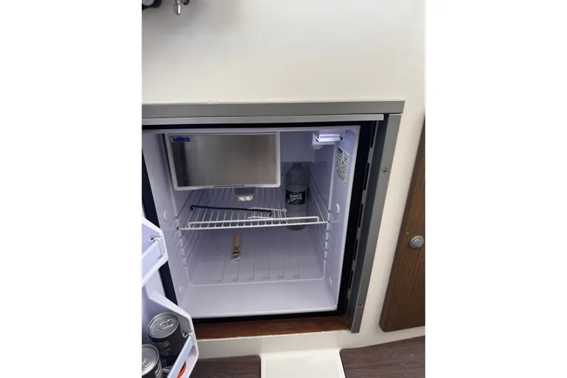 Slide: The Image of Mini fridge inside 2021 Beneteau Antares 8 boat, containing drinks and a small freezer compartment. - 32
