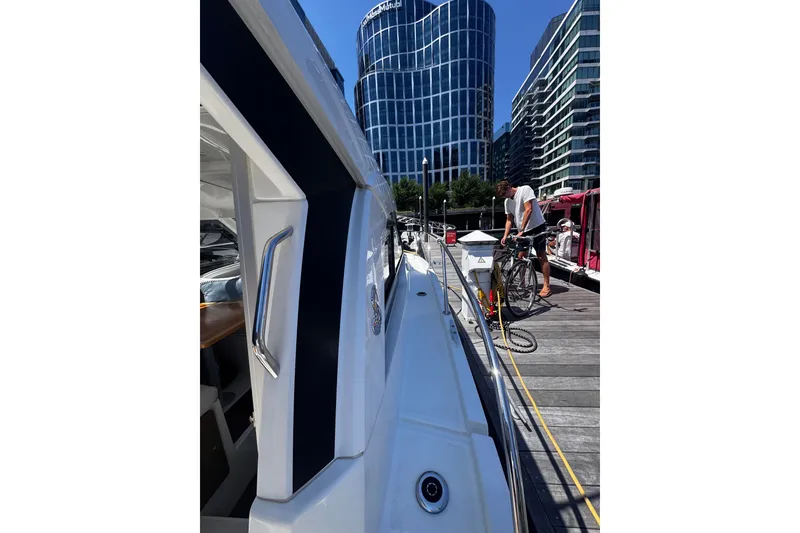 Slide: The Image of 2021 Beneteau Antares 8 docked near modern buildings, with a person on the pier. - 27