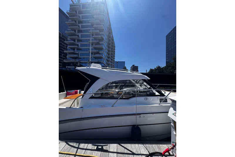 Slide: The Image of Beneteau Antares 8, 2021 model, docked near modern buildings under clear blue sky. - 23