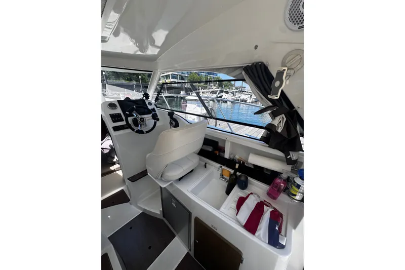 Slide: The Image of Interior view of 2021 Beneteau Antares 8 boat cockpit with steering wheel and marina view. - 14
