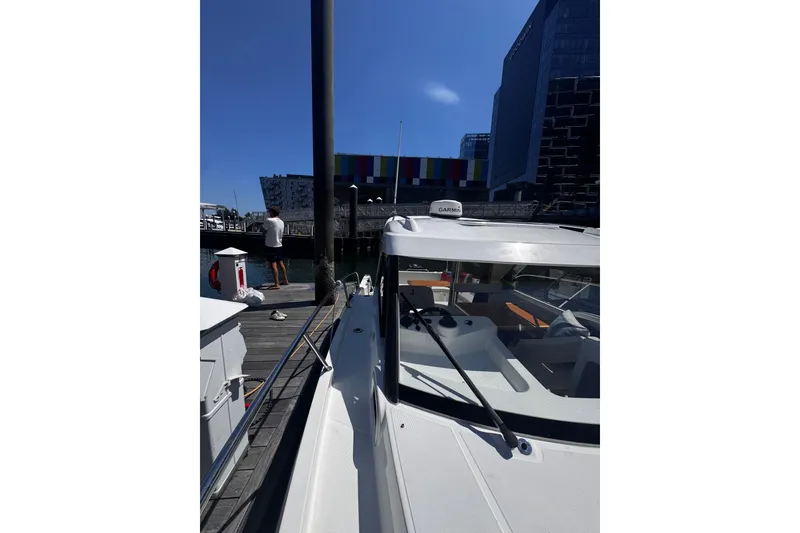 Slide: The Image of 2021 Beneteau Antares 8 docked at a marina with modern buildings in the background. - 29