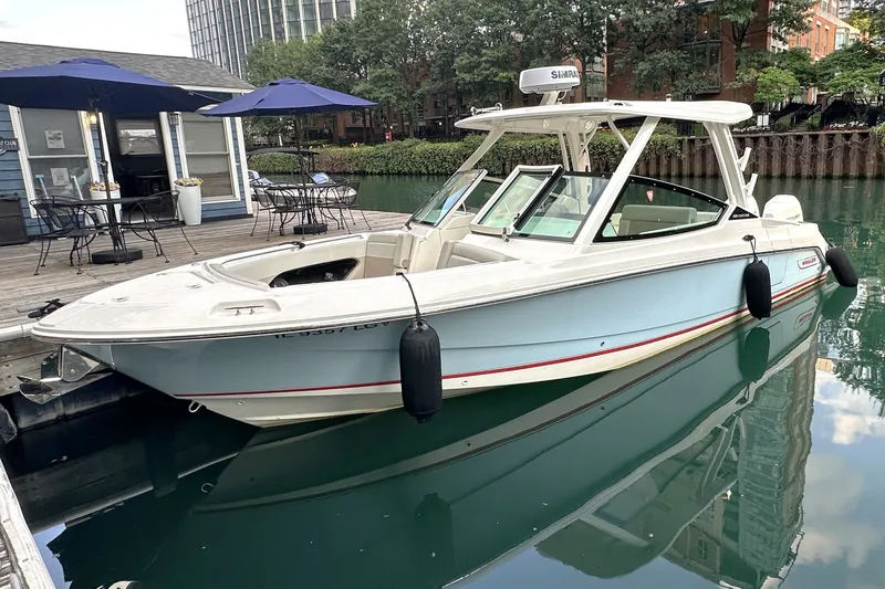 Slide: The Image of 2025 Boston Whaler 280 Vantage docked by a waterfront café with outdoor seating. - 1