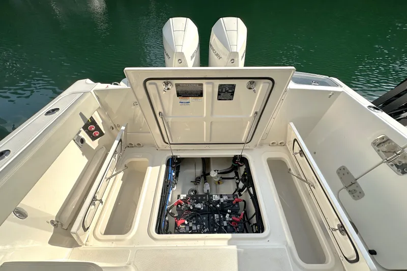 Slide: The Image of 2025 Boston Whaler 280 Vantage boat engine compartment with open hatch, docked on water. - 11