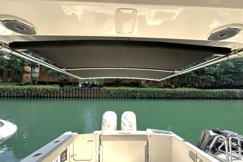 Slide: The Image of Boston Whaler 280 Vantage 2025 boat with canopy, docked on a serene river. - 10