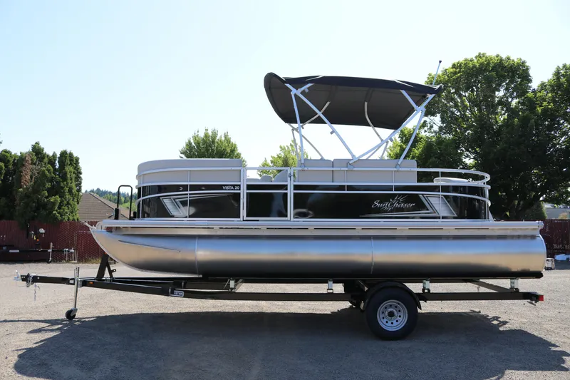Slide: The Image of 2025 SunChaser Vista 20 Fish pontoon boat on trailer, parked outdoors. - 0