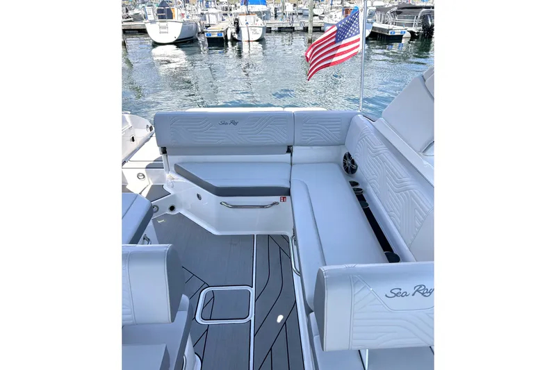 Slide: The Image of Luxurious seating on 2025 Sea Ray SDX 270 Surf boat, docked with American flag. - 6