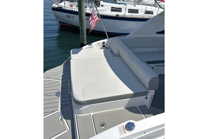 Slide: The Image of 2025 Sea Ray SDX 270 Surf boat with spacious seating, docked near another vessel. - 7