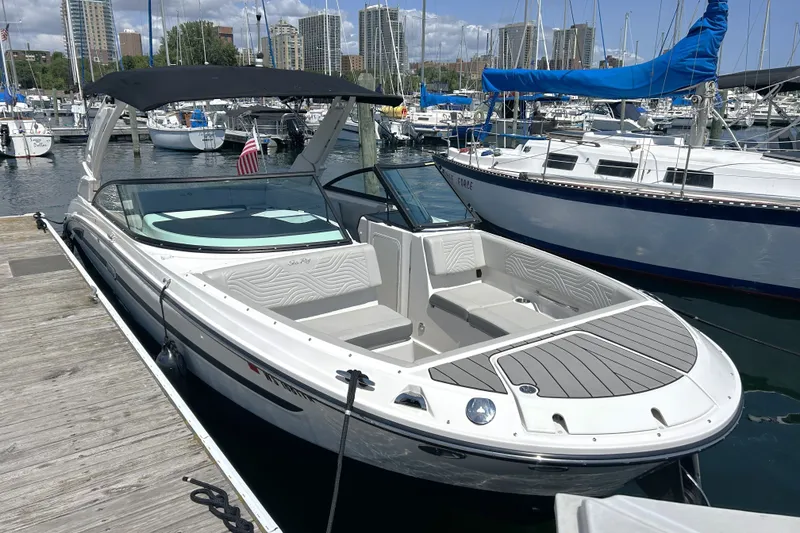 Slide: The Image of 2025 Sea Ray SDX 270 Surf boat docked at marina, surrounded by sailboats. - 2