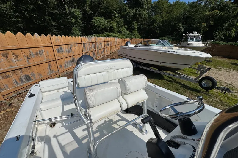 Slide: The Image of 2016 Sea Hunt Triton 188 boat with white seating, parked outdoors near a wooden fence. - 3