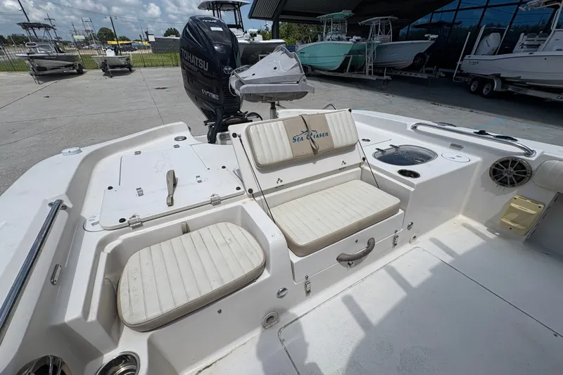 Slide: The Image of 2019 Sea Chaser 26 LX boat interior with seating and Tohatsu engine in a marina setting. - 13