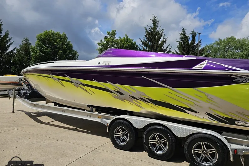 Slide: The Image of 2007 Sunsation 32 Dominator boat with vibrant purple and yellow design on a trailer. - 26