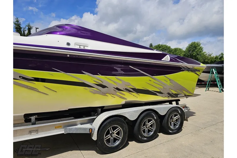 Slide: The Image of 2007 Sunsation 32 Dominator boat with vibrant purple and yellow design on a trailer. - 23