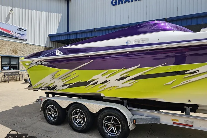 Slide: The Image of 2007 Sunsation 32 Dominator boat with vibrant purple and lime green design on trailer. - 7