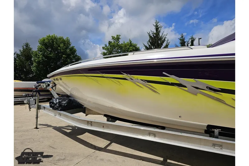 Slide: The Image of 2007 Sunsation 32 Dominator boat on trailer, vibrant yellow and purple design, under cloudy sky. - 22