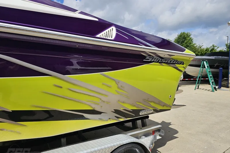 Slide: The Image of 2007 Sunsation 32 Dominator boat with vibrant purple and lime green design on trailer. - 24